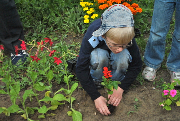 Дети сажают цветочки на территории салона Герон-Кар